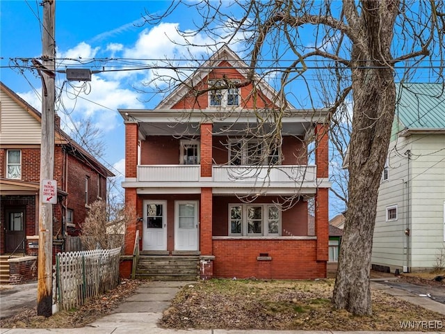 american foursquare style home with entry steps, fence, crawl space, a balcony, and brick siding