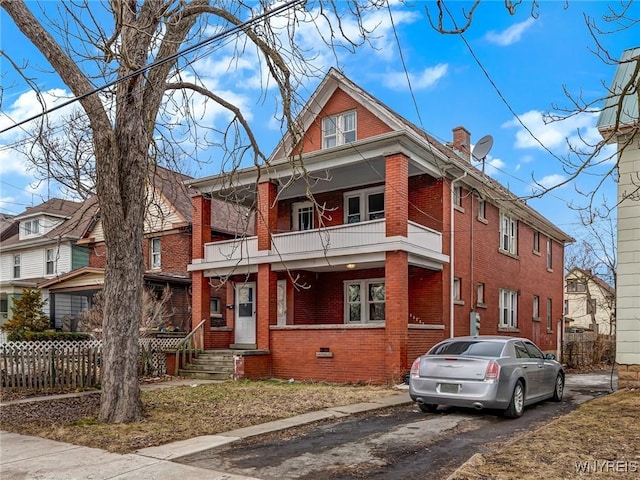 view of front of property featuring a balcony, fence, brick siding, and crawl space