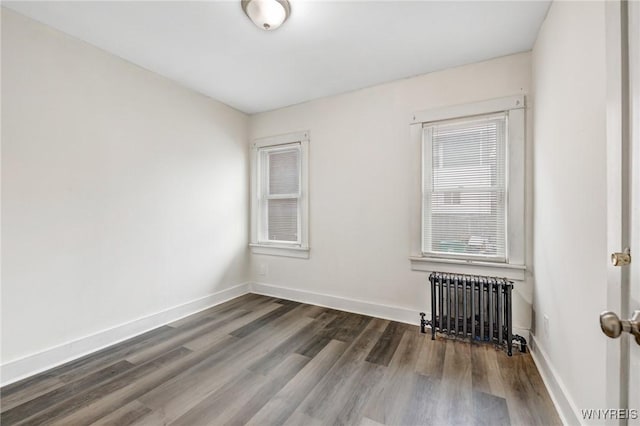 unfurnished room with baseboards, radiator, and dark wood finished floors