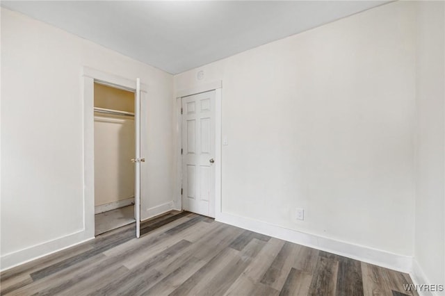 unfurnished bedroom with a closet, baseboards, and wood finished floors