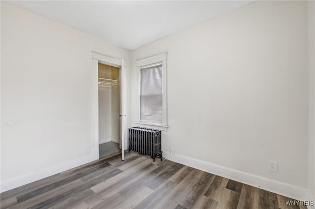 unfurnished room featuring radiator, baseboards, and wood finished floors