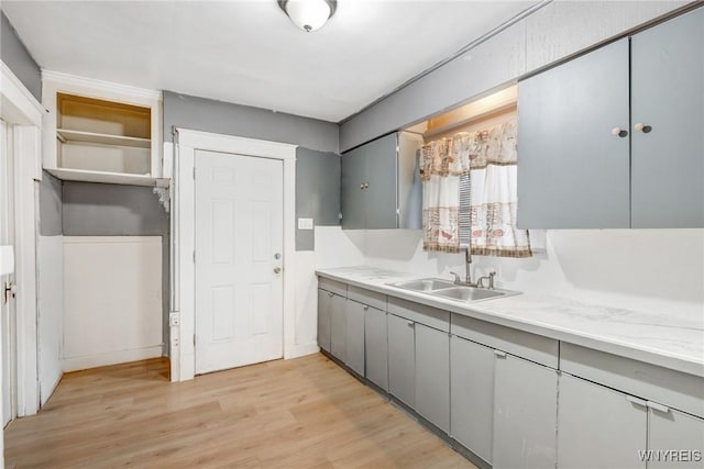 kitchen featuring a sink, light wood-style floors, gray cabinetry, and light countertops