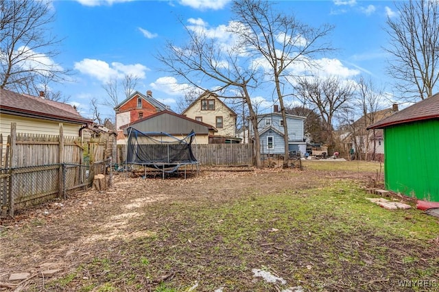 view of yard with an outbuilding, a trampoline, and a fenced backyard