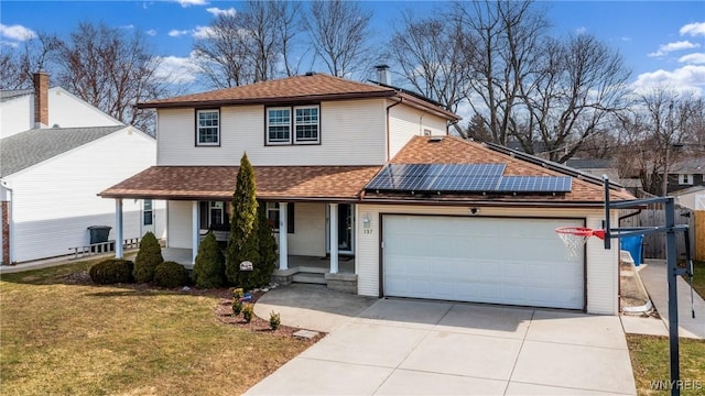 traditional-style home with roof with shingles, solar panels, covered porch, a front lawn, and a garage