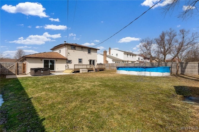 view of yard featuring a fenced backyard, a fenced in pool, a hot tub, and a deck