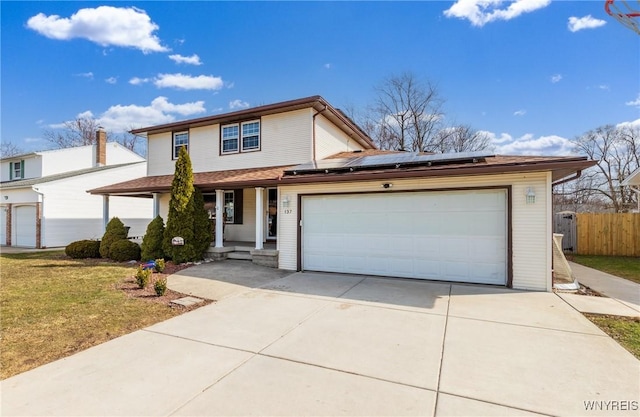 traditional-style home with fence, driveway, solar panels, an attached garage, and covered porch