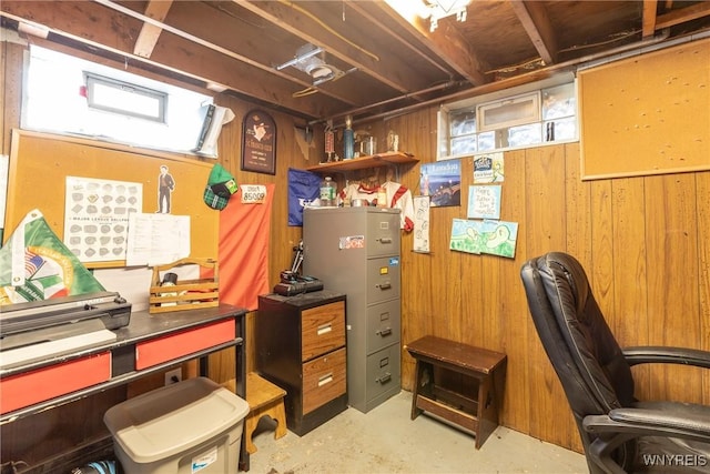 home office featuring concrete flooring and wood walls