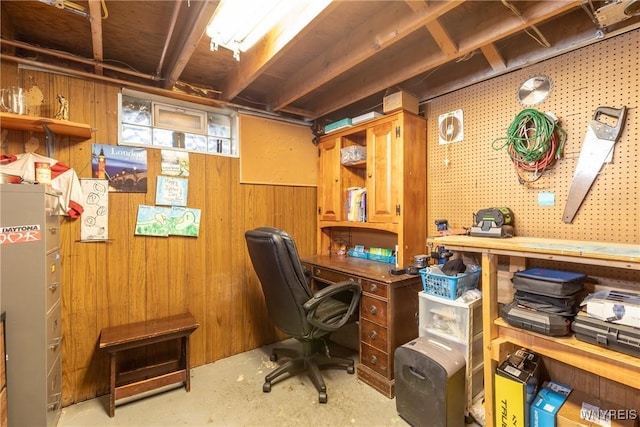 home office with unfinished concrete floors, a workshop area, and wood walls