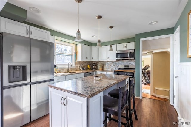 kitchen with a kitchen bar, white cabinets, a center island, and stainless steel appliances