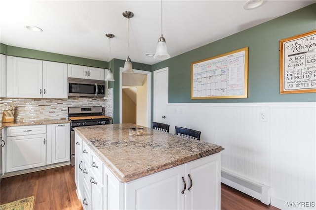 kitchen with a center island, white cabinets, stainless steel appliances, and light stone countertops