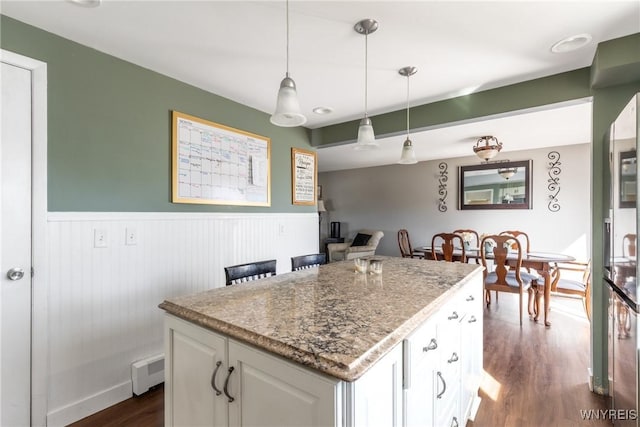 kitchen featuring a wainscoted wall, pendant lighting, a kitchen island, dark wood finished floors, and white cabinets