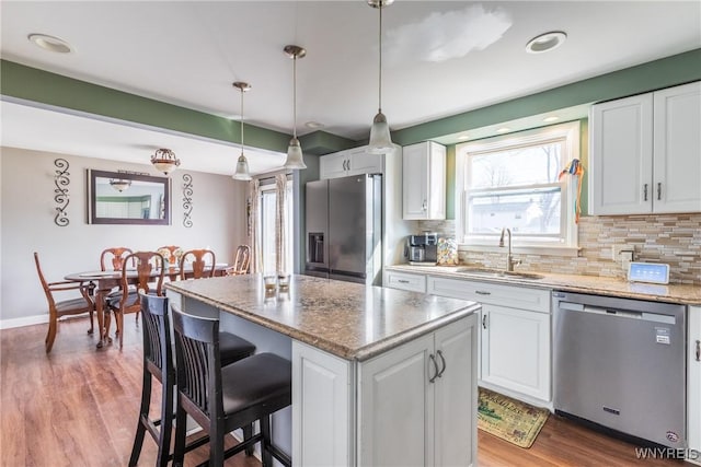 kitchen featuring a sink, a kitchen island, white cabinetry, and stainless steel appliances