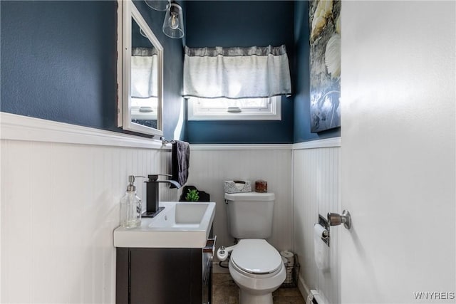 bathroom featuring wainscoting, toilet, and vanity