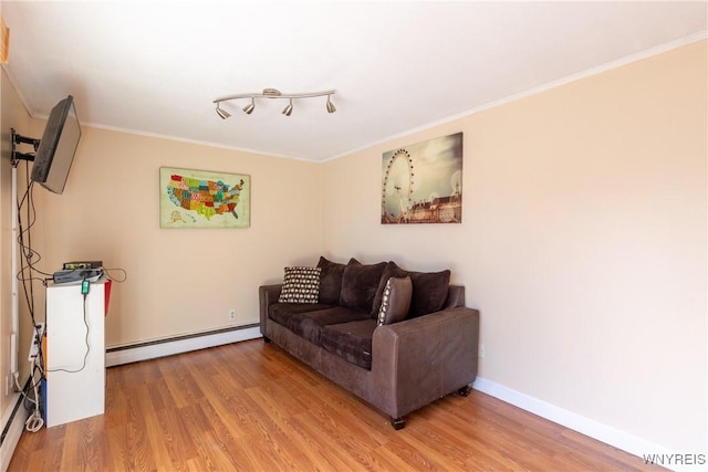 living room with light wood-type flooring, baseboards, baseboard heating, and crown molding