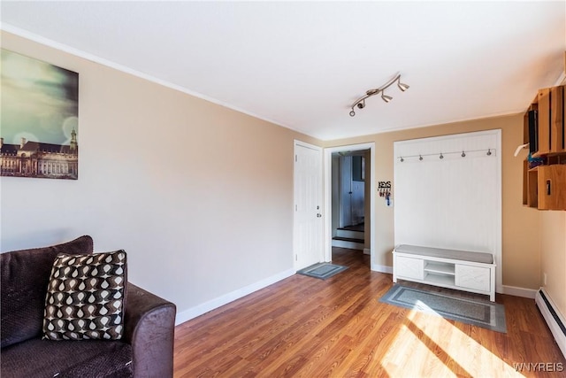 interior space featuring baseboards, baseboard heating, wood finished floors, and track lighting