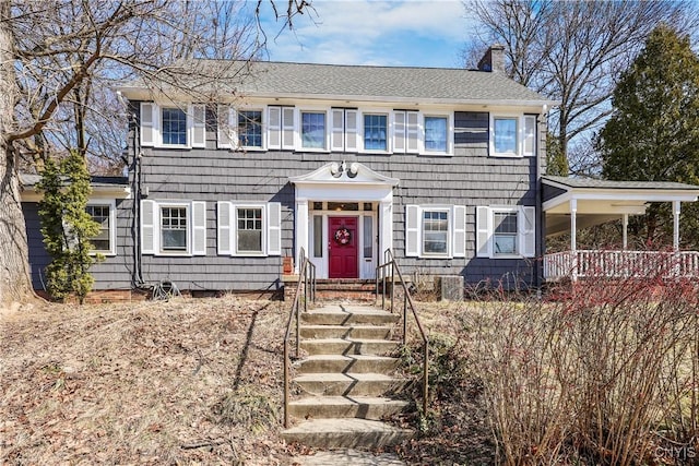 colonial inspired home featuring a shingled roof and a chimney