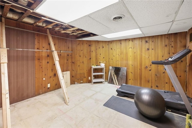 exercise area with tile patterned floors, wooden walls, a paneled ceiling, and visible vents