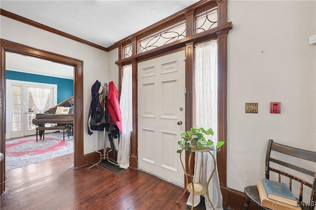 foyer featuring a textured ceiling, dark wood-type flooring, baseboards, and ornamental molding