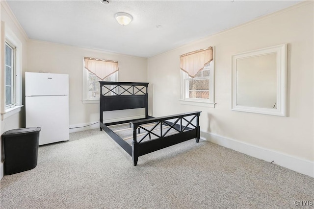 carpeted bedroom with baseboards, multiple windows, and freestanding refrigerator