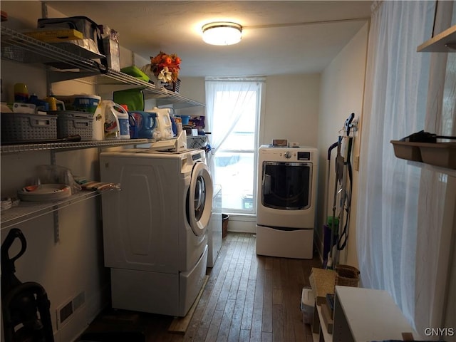 laundry room featuring visible vents, washing machine and dryer, dark wood finished floors, and laundry area