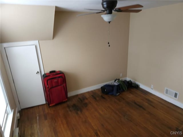 spare room with a ceiling fan, wood finished floors, visible vents, and baseboards