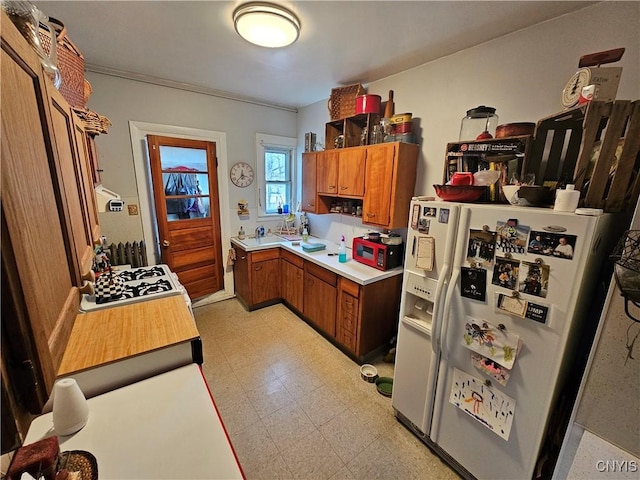 kitchen featuring brown cabinetry, light floors, white appliances, and light countertops