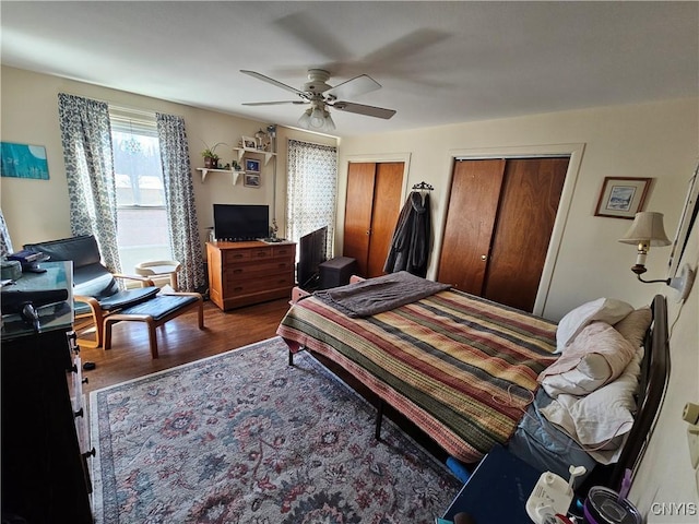 bedroom with multiple closets, wood finished floors, and a ceiling fan