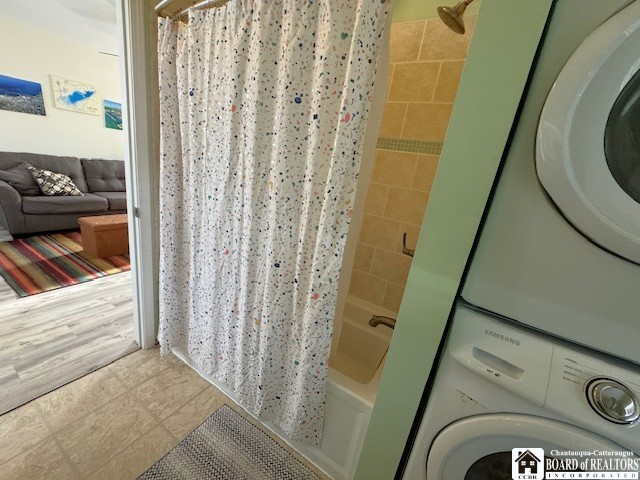 bathroom with stacked washer / dryer and shower / bathtub combination with curtain