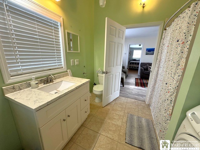 full bathroom with a shower with shower curtain, toilet, and vanity