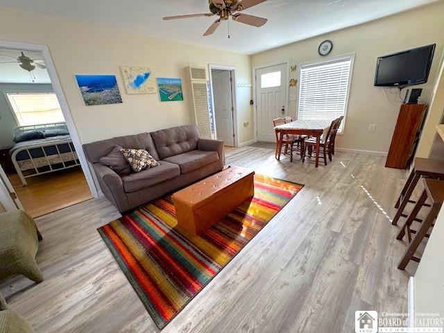 living area with baseboards, ceiling fan, and wood finished floors