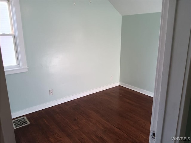 empty room with dark wood finished floors, visible vents, and baseboards