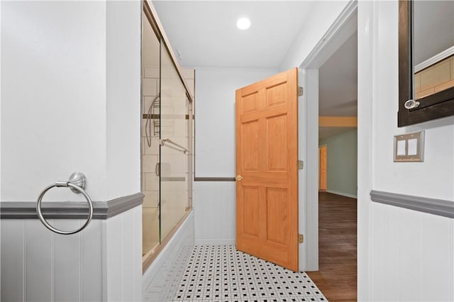 bathroom with shower / bath combination with glass door and wainscoting