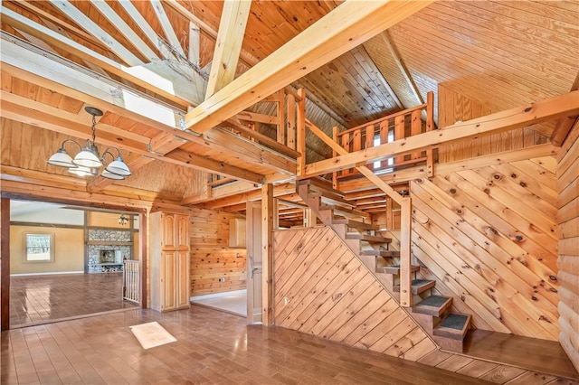 interior space featuring a chandelier, wood ceiling, wood walls, and stairs