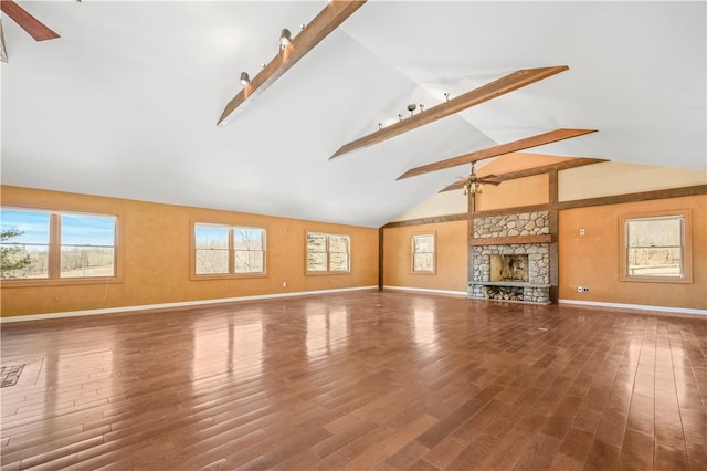 unfurnished living room with baseboards, ceiling fan, a stone fireplace, wood finished floors, and high vaulted ceiling