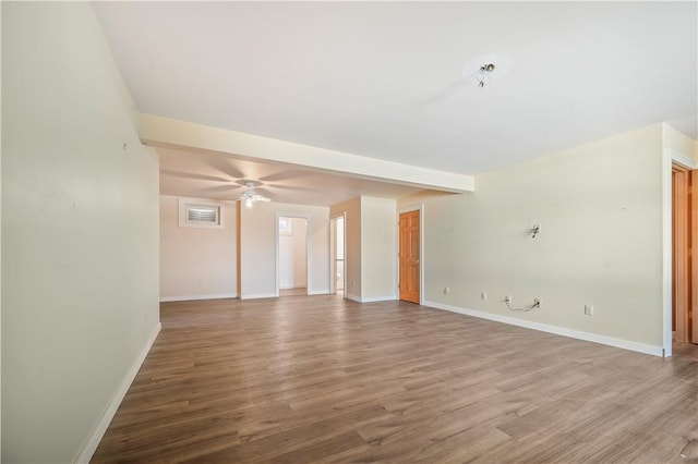 empty room with beamed ceiling, baseboards, wood finished floors, and a ceiling fan