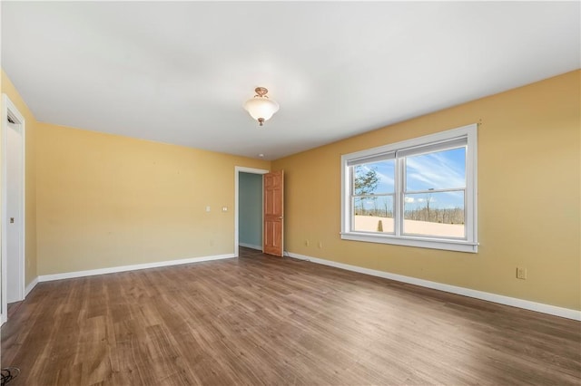 spare room with baseboards and wood finished floors