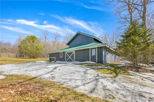 exterior space with metal roof, a barn, board and batten siding, and an outdoor structure