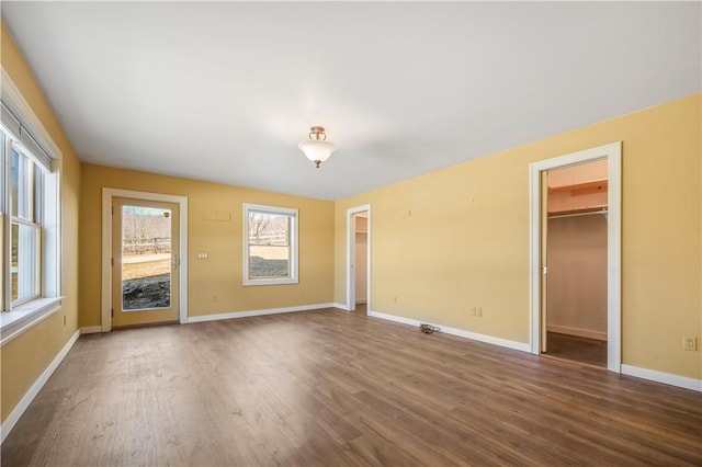 unfurnished living room with baseboards and wood finished floors