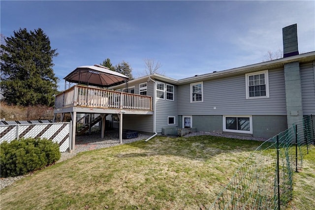 rear view of property with a chimney, a deck, fence, a gazebo, and stairs