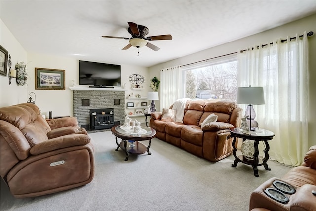 living room with a stone fireplace, carpet, and a ceiling fan