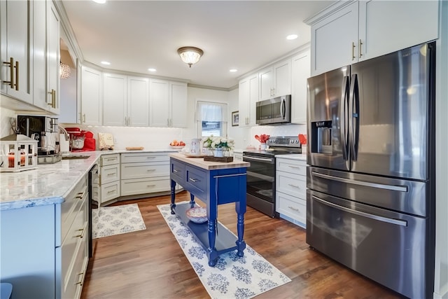 kitchen with dark wood finished floors, recessed lighting, appliances with stainless steel finishes, white cabinetry, and wood counters