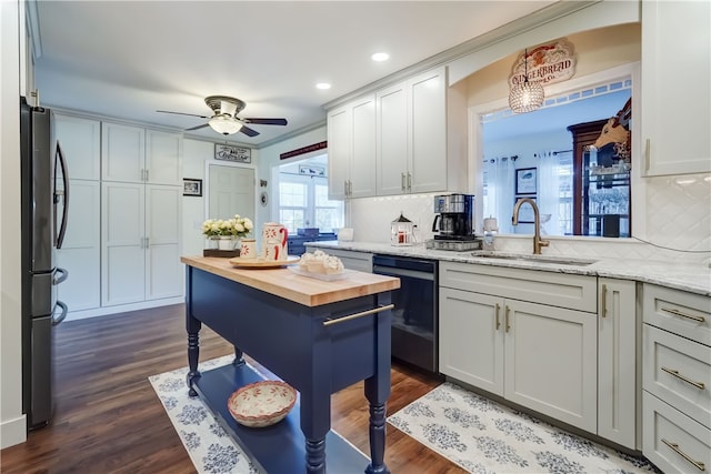 kitchen featuring a sink, freestanding refrigerator, butcher block counters, dishwasher, and ceiling fan