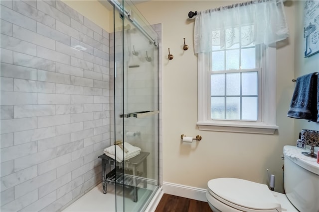 bathroom featuring a stall shower, toilet, baseboards, and wood finished floors