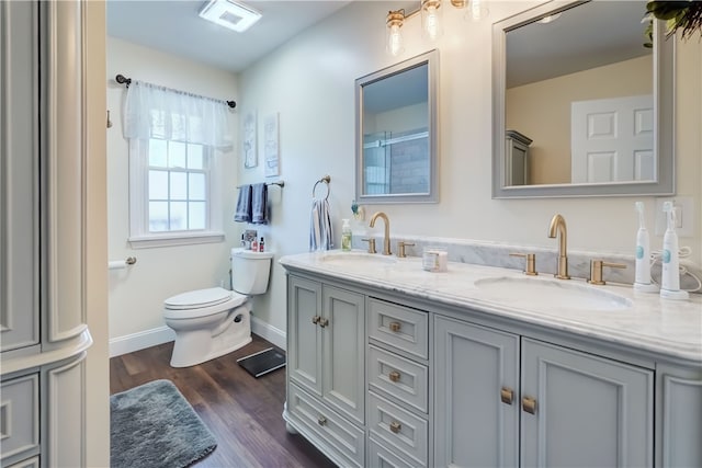 bathroom with a sink, toilet, wood finished floors, and double vanity