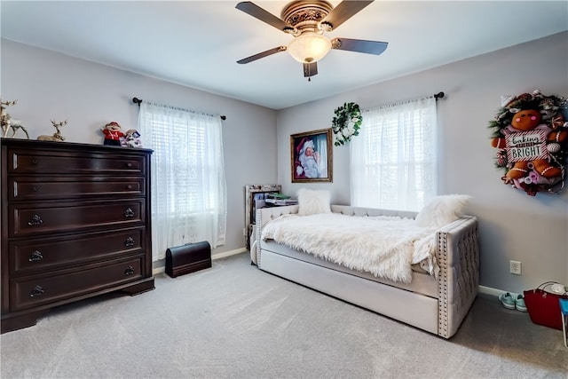 bedroom with multiple windows, light colored carpet, and baseboards