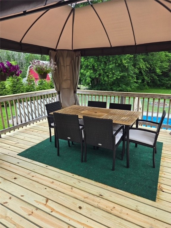 wooden terrace featuring a gazebo, a swimming pool, and outdoor dining space