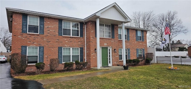 view of front of property featuring brick siding, a front lawn, and fence