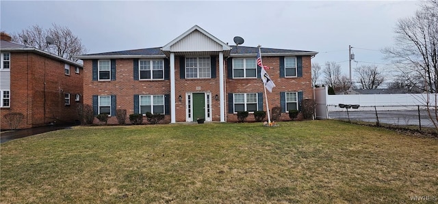 view of front facade with brick siding, a front yard, and fence