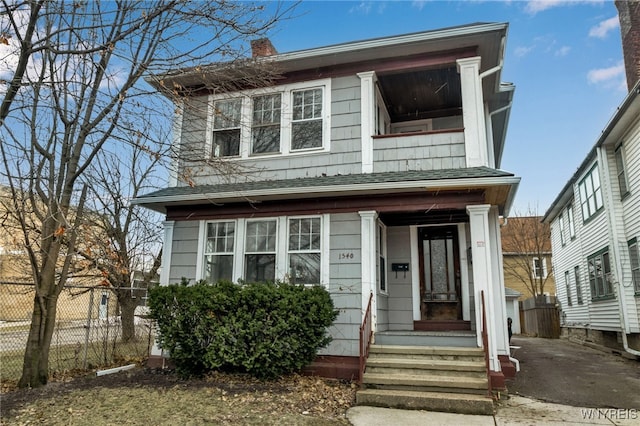 view of front of home with a chimney, a balcony, and fence