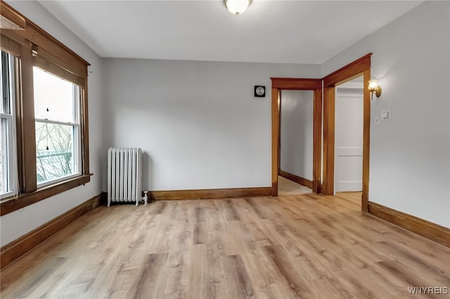 spare room with radiator heating unit, light wood-style floors, and baseboards